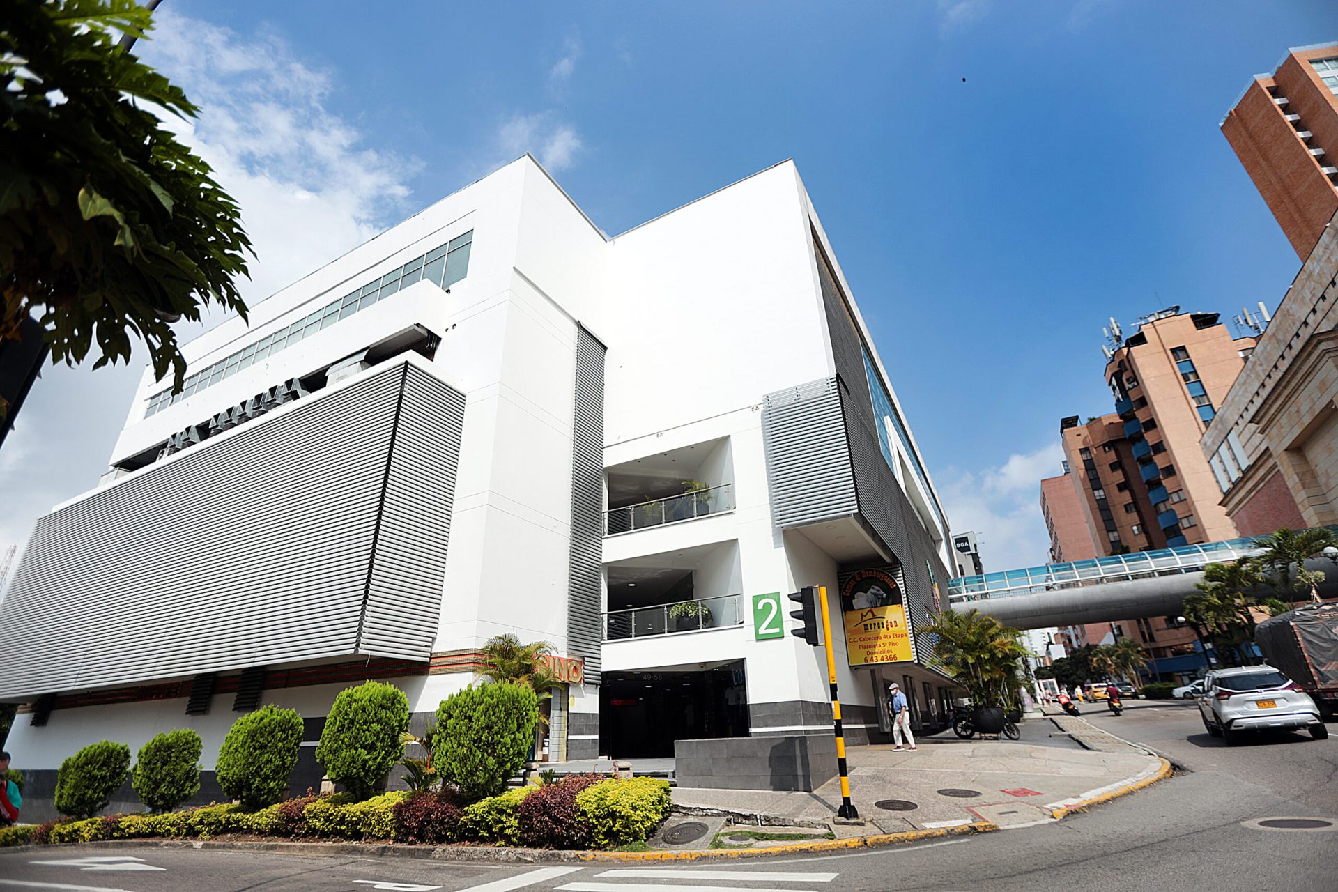 Esquina de acceso al centro comercial, con el puente peatonal al fondo